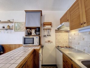 A compact kitchen with wooden cabinets, a microwave, a refrigerator, and a tiled backsplash. - 100m from resort center, 2nd floor, balcony, tv, 25m², La Rosière (La Rosière Montvalezan)