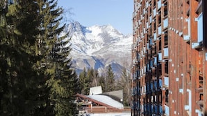 A building with a modern architectural design, featuring a series of balconies and a view of snow-capped mountains in the background. - 50m from resort center, 7th floor, balcony, tv, 24m², Les Arcs (Les Arcs)