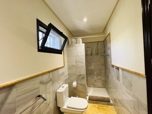 A modern bathroom with a toilet, shower, and towel rack.