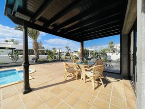 Relax by the pool surrounded by lush greenery and enjoy dining or socializing at the outdoor table.