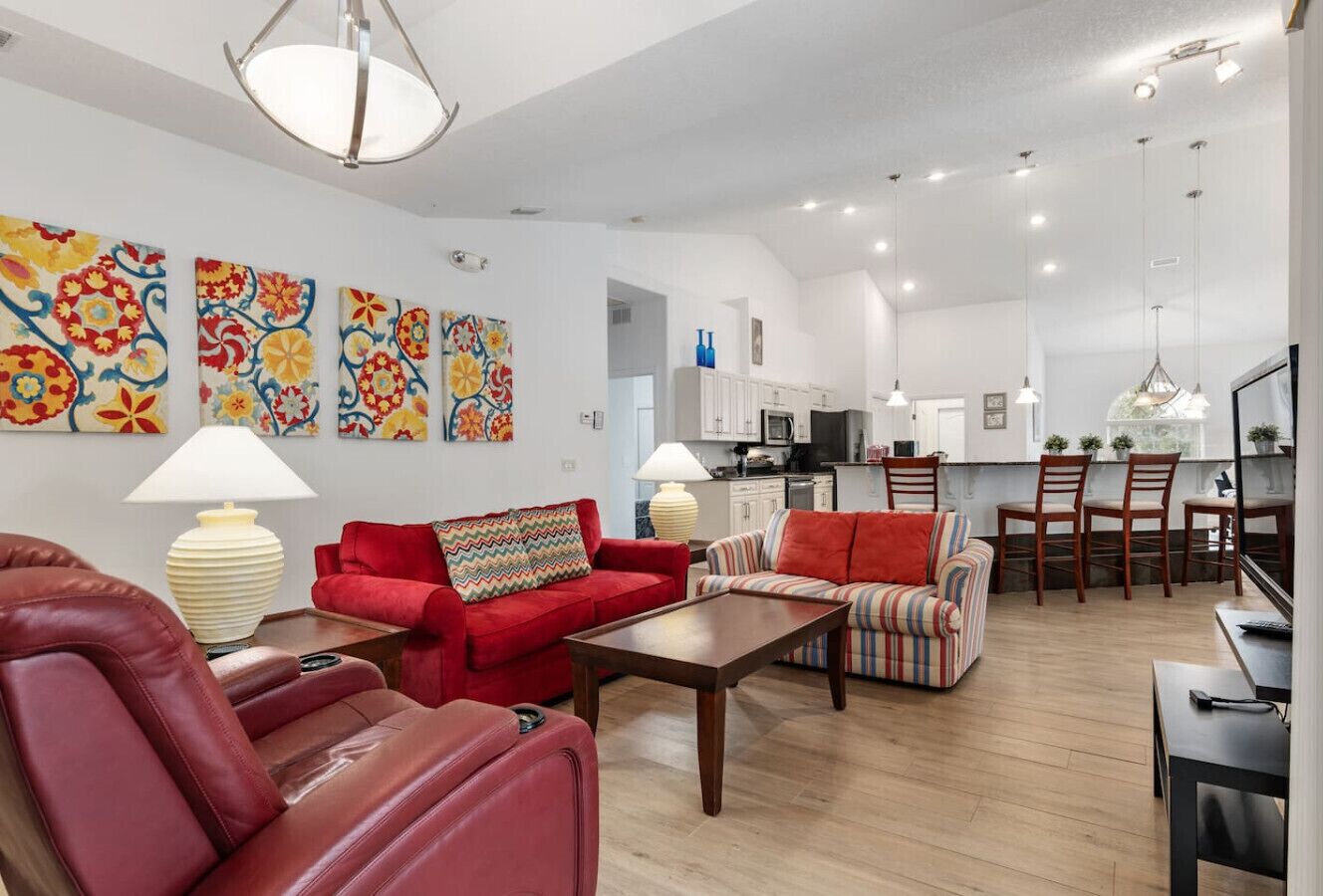 Een moderne woonkamer met rode banken, een houten salontafel en een keuken op de achtergrond.