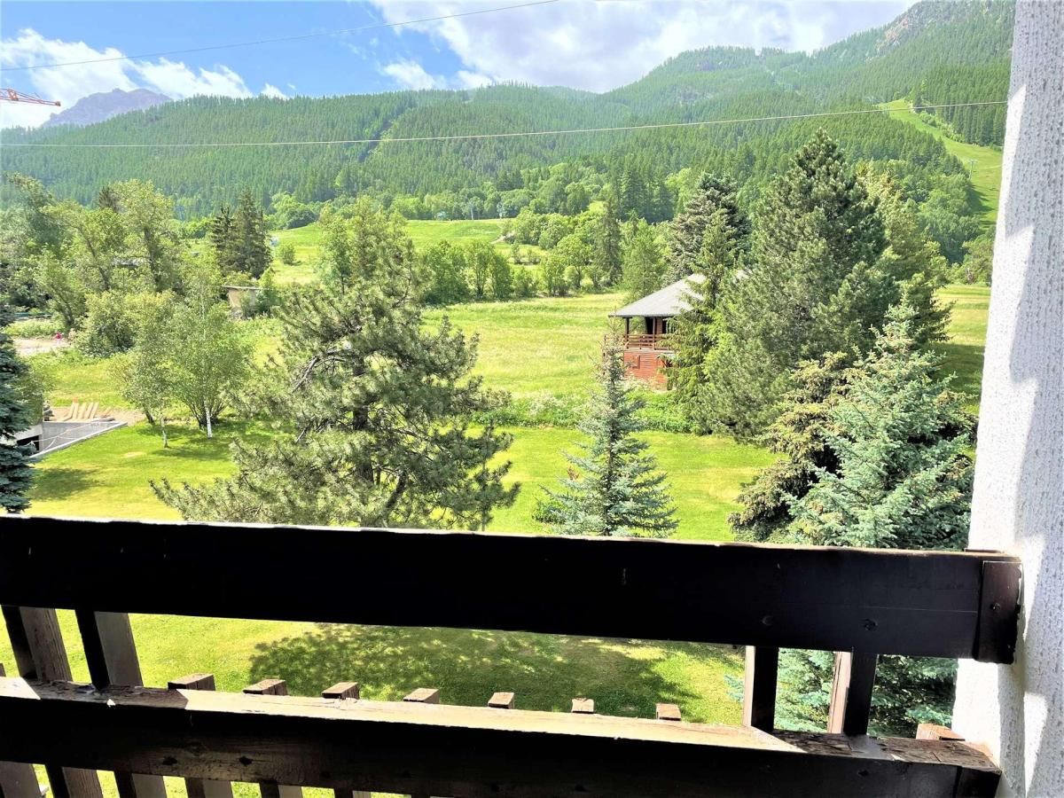 A balcony with a view of a green landscape, including trees and a small building.