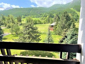 Un balcón con vistas a un paisaje verde, que incluye árboles y un pequeño edificio.