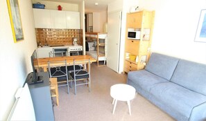 Un espacio habitable compacto con kitchenette, comedor y sofá.