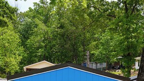 A small blue shed with a door marked '2', two blue chairs, a trash bin, and a picnic table.