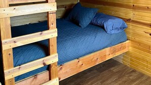 A bunk bed with a wooden ladder, blue bedding, and a wooden interior.