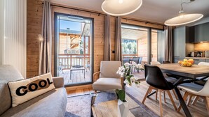 Una sala de estar moderna con sofá, una mesa de comedor y vistas a una terraza de madera.