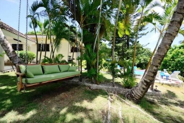 Relax in a serene garden setting with a peaceful swing suspended among lush greenery.