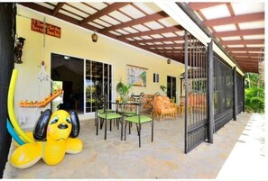 Relax in the shaded patio area, surrounded by comfortable seating and a charming sculpture.