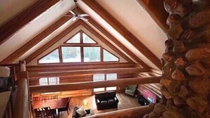 Ein Loft-Zimmer mit schrägem Dach, Holzbalken und einer Steinwand.