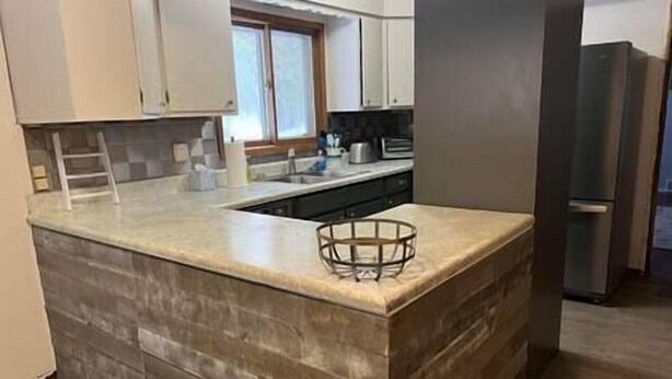 A kitchen with a granite countertop, a built-in sink, and a stainless steel refrigerator. - Wagner Creek Hideaway (Munising Township)