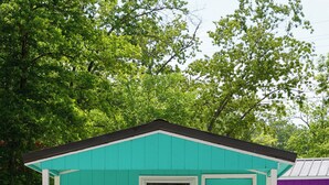 A small, turquoise wooden cabin with a door marked "3", a window, and a bench outside. - Franky and Louie's Turquoise Cabin 3 (Sunrise Beach)