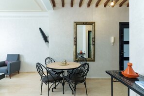 Zona pranzo con tavolo rotondo, quattro sedie, uno specchio e un tagine marocchino su un tavolino.