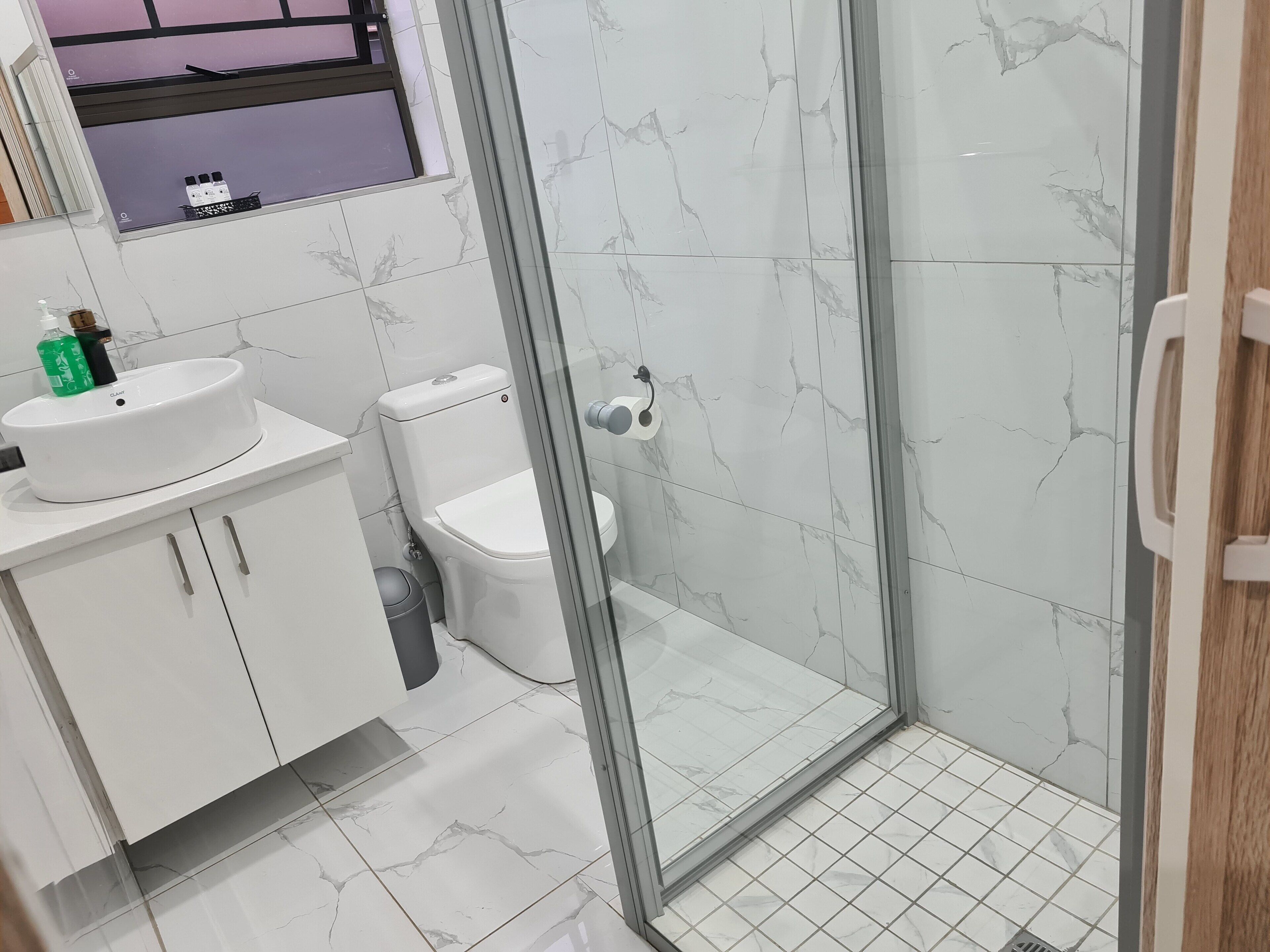 A bathroom with a toilet, sink, and shower area.