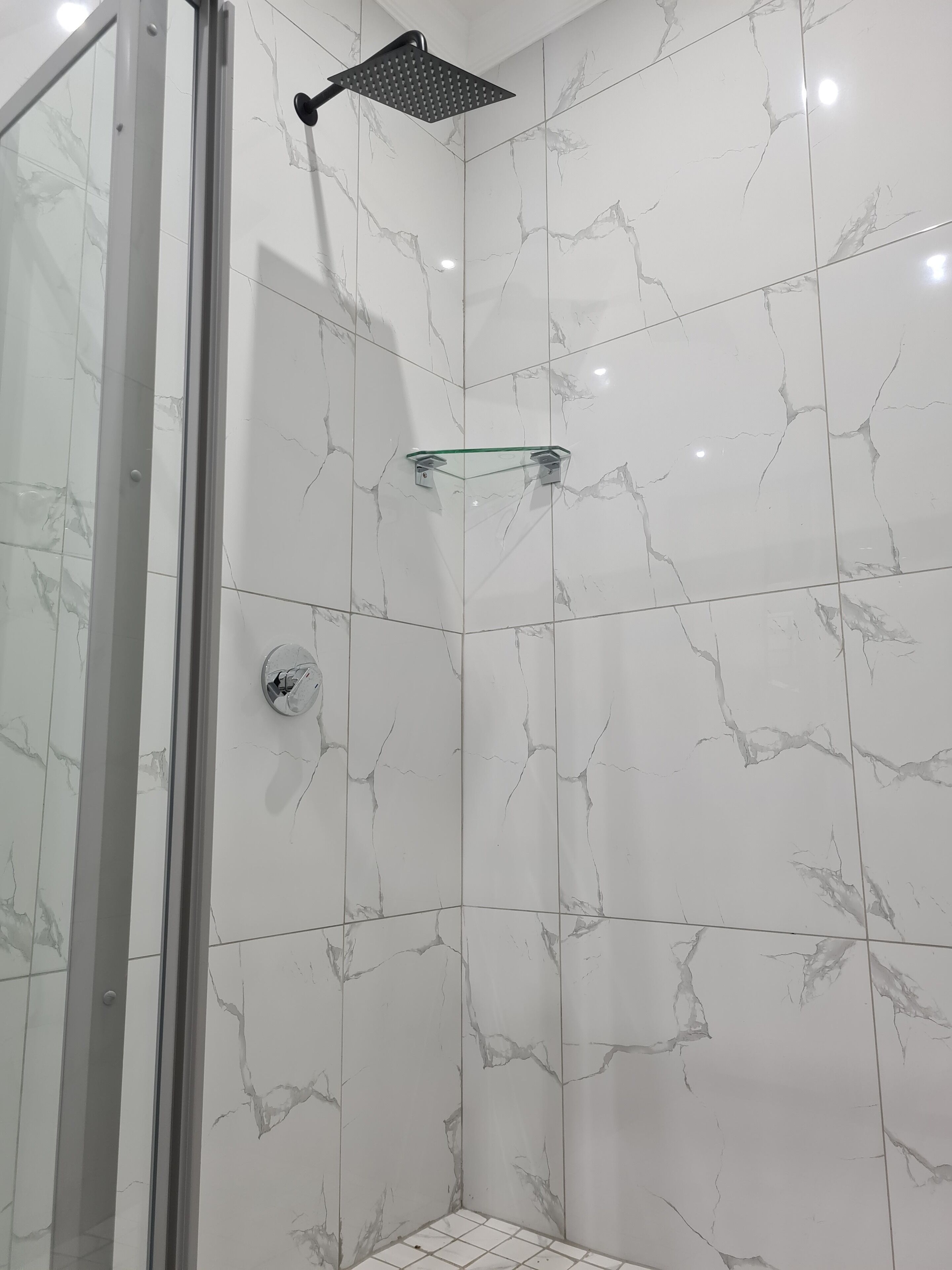 A shower with a glass door and a square showerhead.