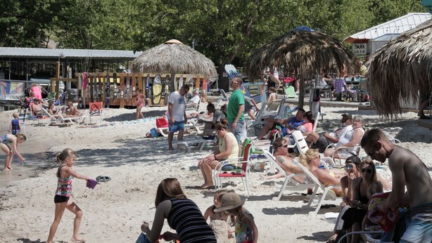 Une plage bondée où les gens se prélassent au soleil et où des enfants jouent.