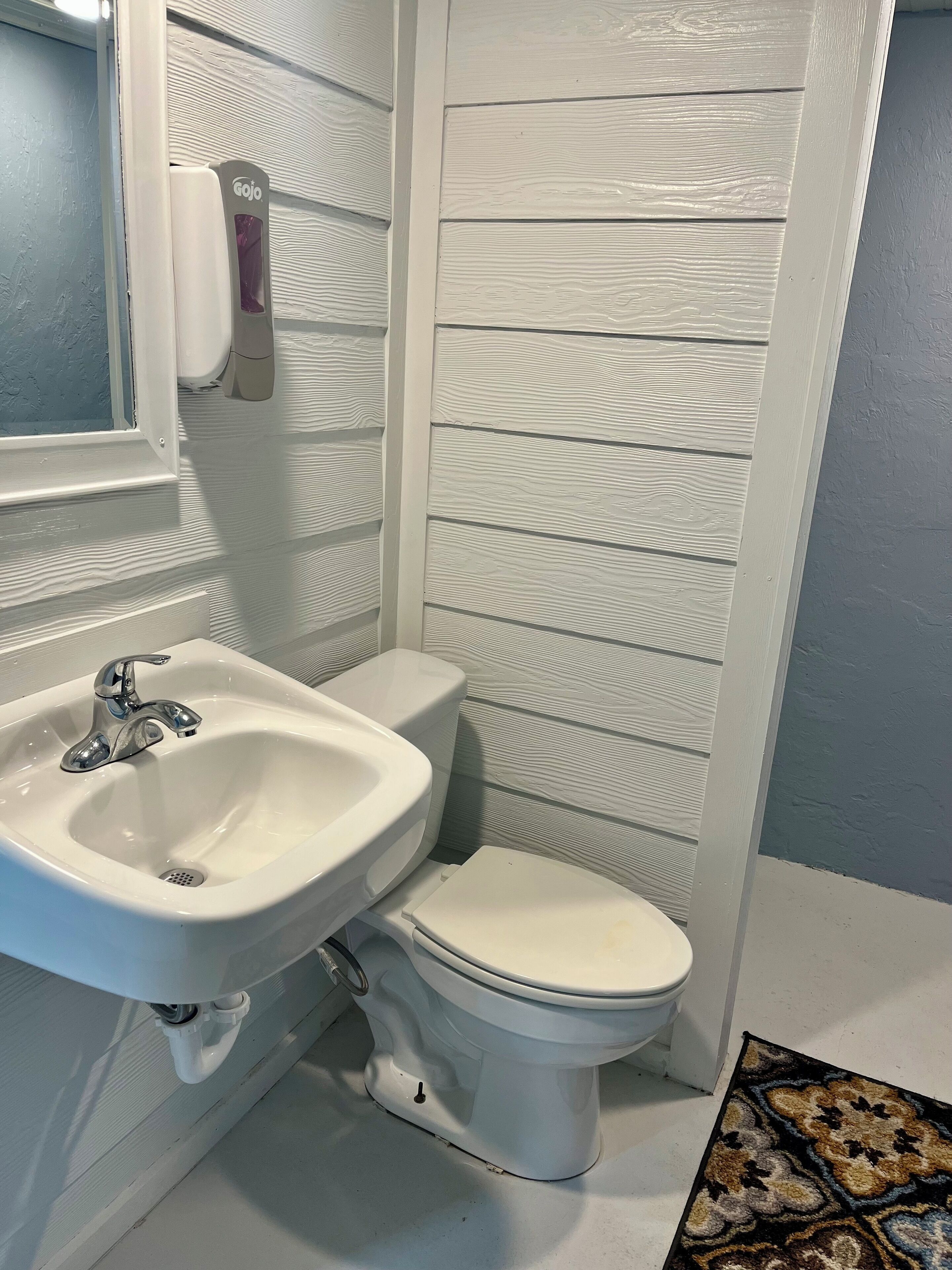 Un baño con lavamanos blanco, inodoro y pared con diseño.
