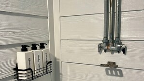 Een badkamer met een douche, een handdroger en een rek voor zeepdispensers.
