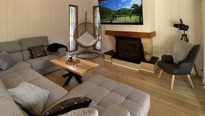 A modern living room with a sectional sofa, a wooden coffee table, a fireplace, and a television mounted on the wall. - la villa familiale la palmyre (Les Mathes)