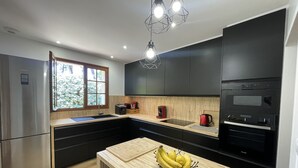 A modern kitchen with black cabinets, a stainless steel refrigerator, a built-in oven, and a wooden countertop. - la villa familiale la palmyre (Les Mathes)