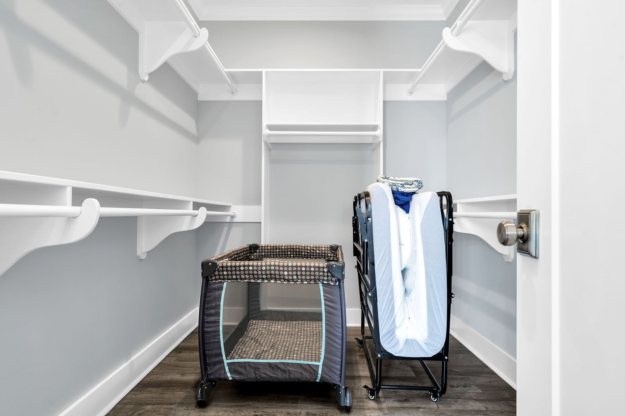 A compact room with a small enclosed playpen, a drying rack, and a door with a handle.