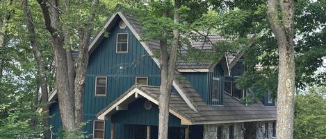 A large, dark green wooden house with multiple windows and a porch.