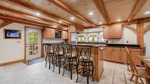 A kitchen with wooden cabinets, a bar area with stools, and a large island. - Perfect Mountain Retreat; minutes from all the Laurel Highlands has to offer! (Somerset)