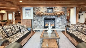 A cozy living room with a stone fireplace, wooden beams, and patterned sofas. - Perfect Mountain Retreat; minutes from all the Laurel Highlands has to offer! (Somerset)
