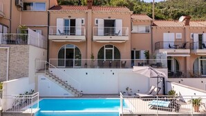 A two-story building with a swimming pool, balconies, and outdoor seating. - Villa with Swim/Heated Pool and charming Bay view (Zaton)