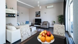 A modern living room with a sofa, armchairs, a coffee table with fruit, a TV, and a plant. - Villa with Swim/Heated Pool and charming Bay view (Zaton)