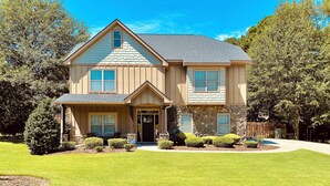 A two-story house with a stone facade, a front porch, and a well-maintained lawn. - Beautiful 5 BR, 3 BA, home only minutes away from the Masters and Peach Jam! (North Augusta)