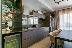 Una cocina moderna con refrigerador empotrado, estufa a gas y comedor con mesa y sillas.