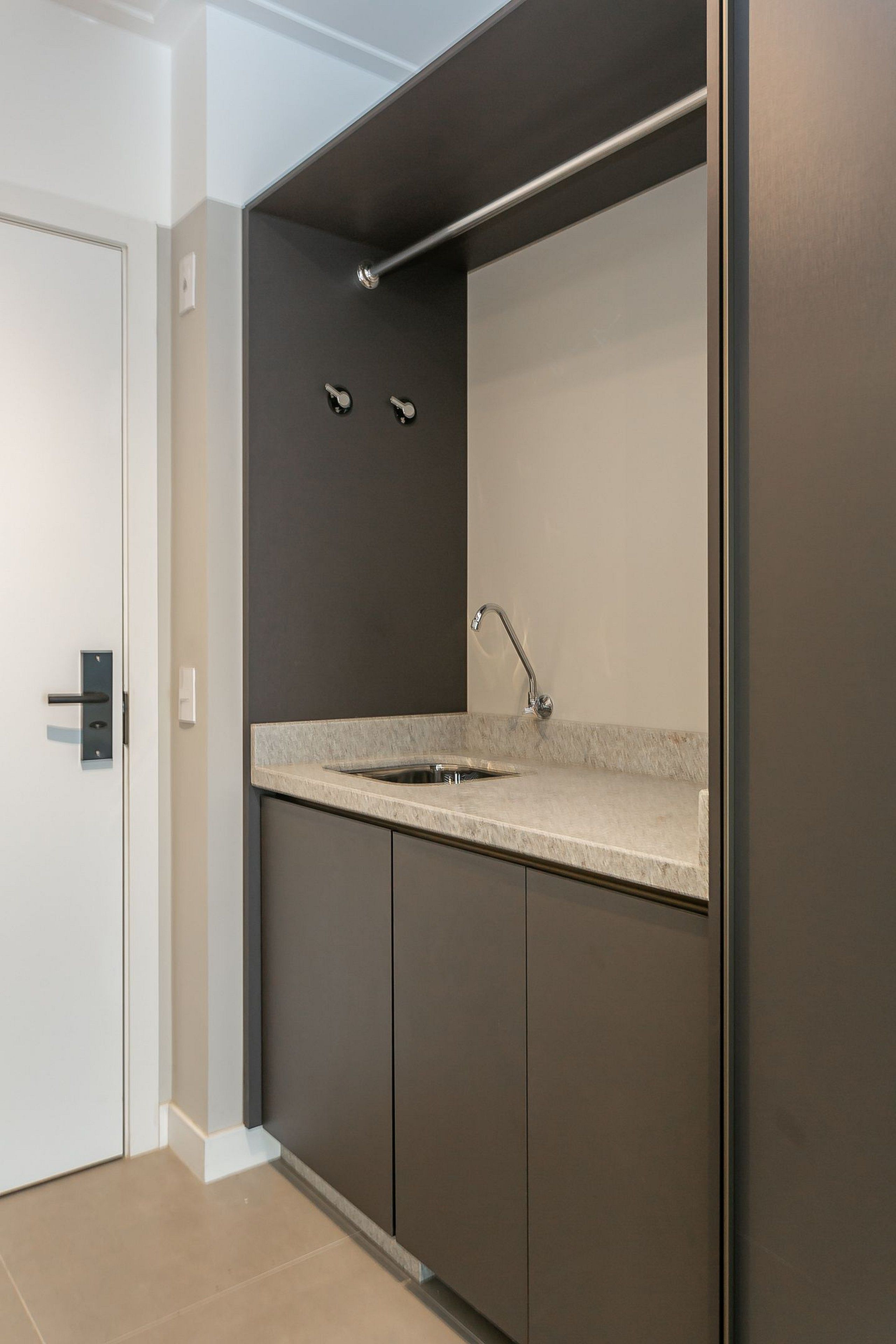 A modern kitchen with a built-in sink, dark cabinetry, and a white door.