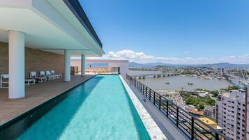 A rooftop pool with a city view, white columns, and lounge chairs.