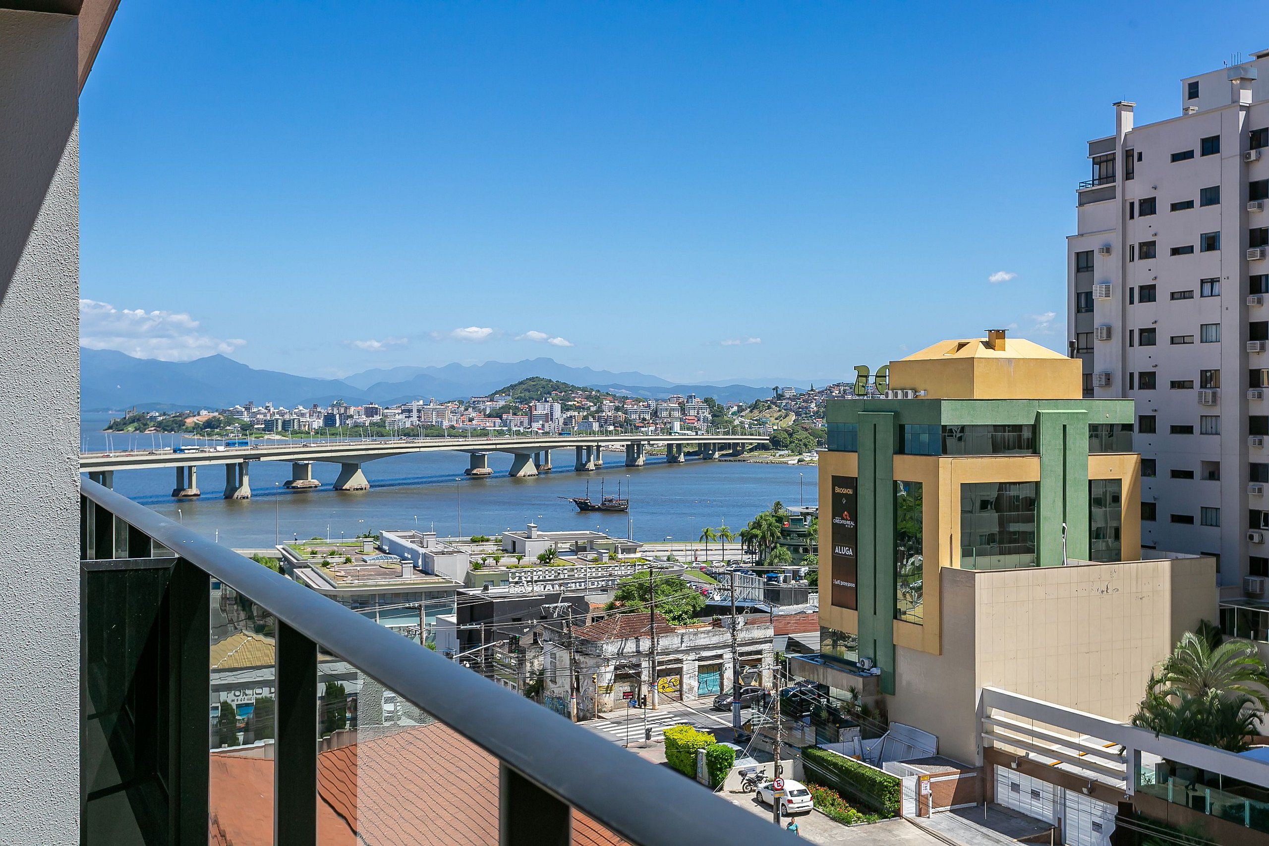 A cityscape with a river, a bridge, and a building with a yellow and green facade.