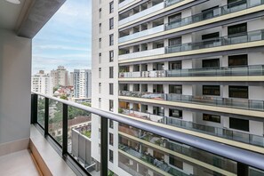 A modern multi-story residential building with balconies, large windows, and a clear view of the surrounding cityscape. - Studios Tower by Viva - Prédio com piscina no rooftop no centro de Floripa (Florianópolis)