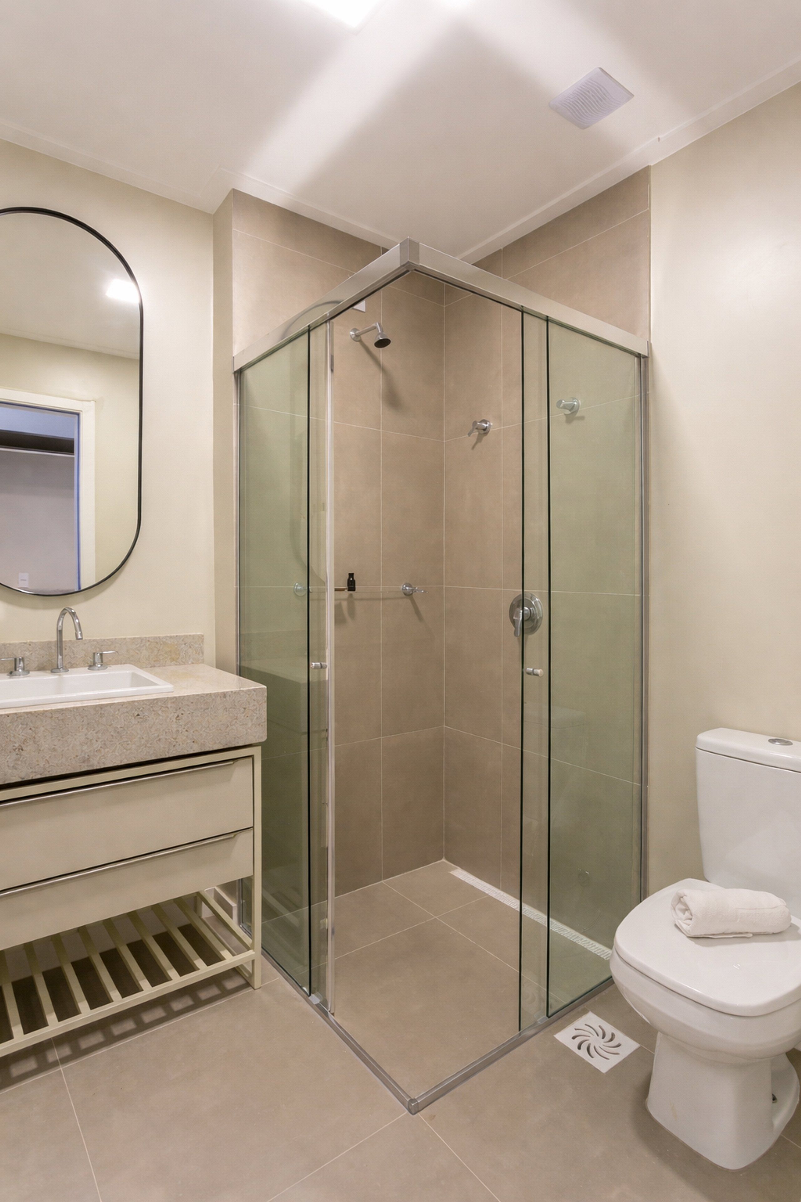 A bathroom with a glass-enclosed shower, a sink with a mirror, and a toilet.
