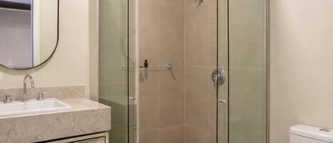 A bathroom with a glass-enclosed shower, a sink with a mirror, and a toilet.