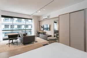 Una moderna camera d'albergo con una grande finestra, un letto, una scrivania, un divano e una TV.