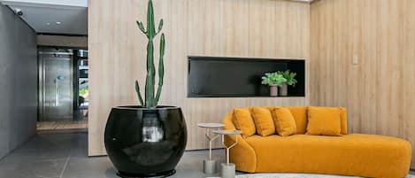 A modern interior with a large black planter, a yellow sofa, and a small table.