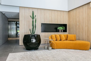 A modern interior with a large black planter, a yellow sofa, and a small table.