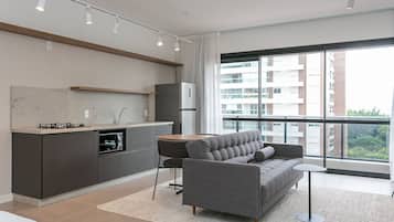 A modern apartment with a kitchen, sofa, and large windows.