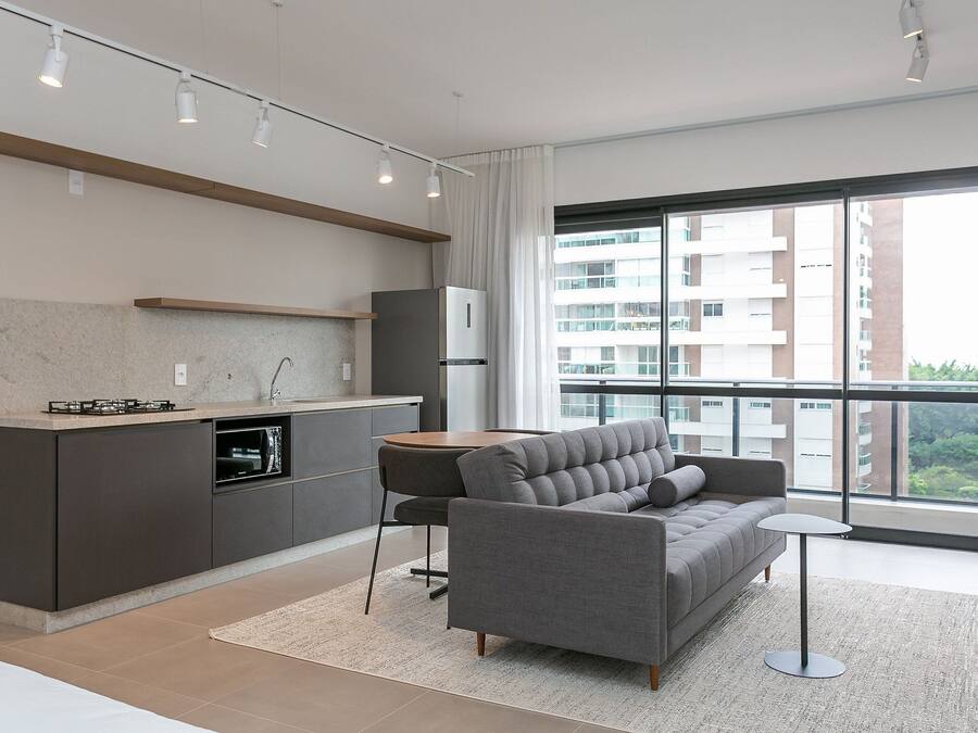 A modern apartment with a kitchen, sofa, and large windows.