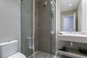 Un bagno moderno con doccia vetrata, un water bianco e un lavabo con specchio sopra.
