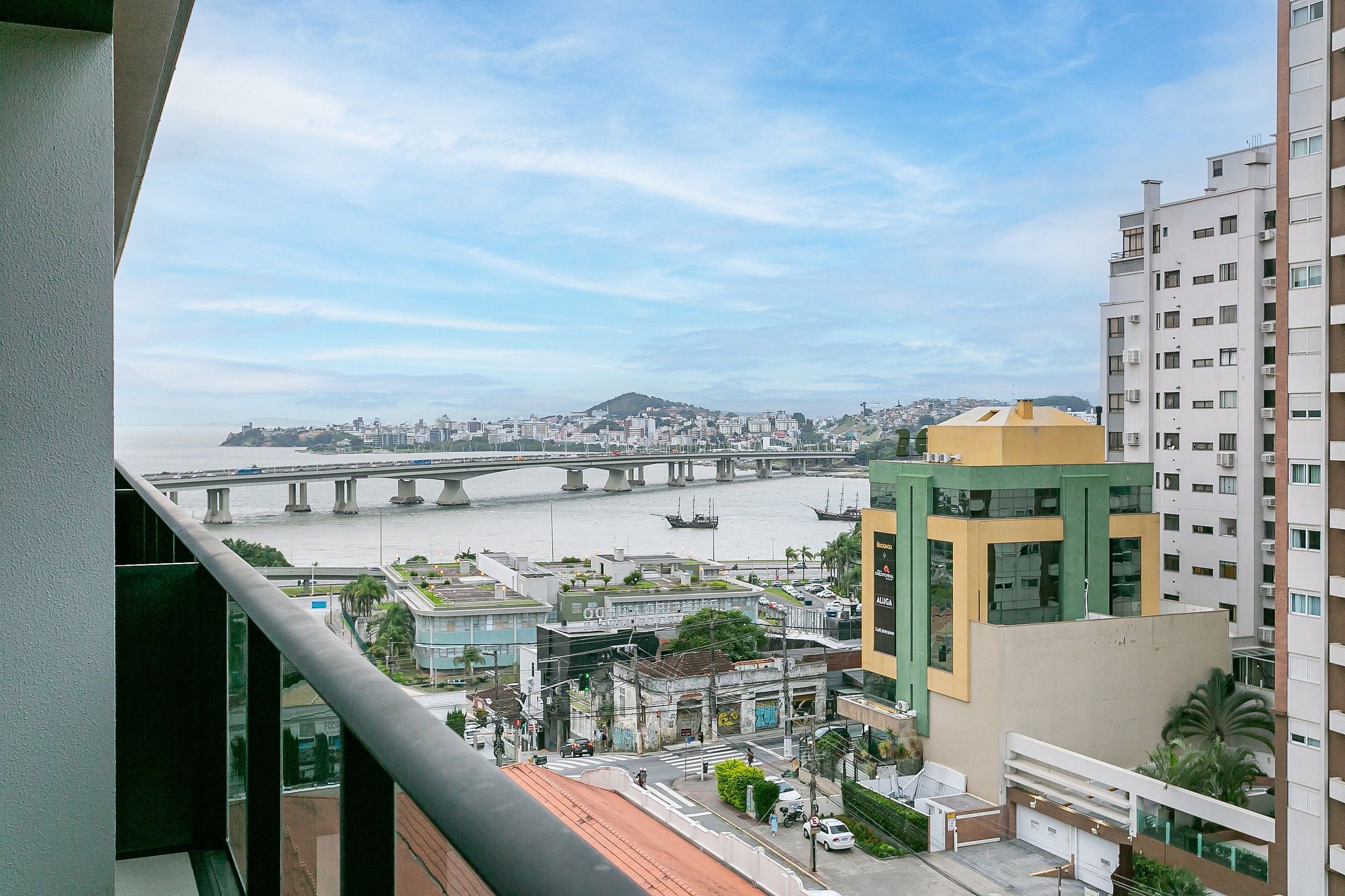 Un edificio alto con vista a un río y un puente a lo lejos.
