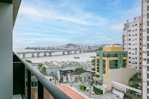 Un edificio alto con vista a un río y un puente a lo lejos.