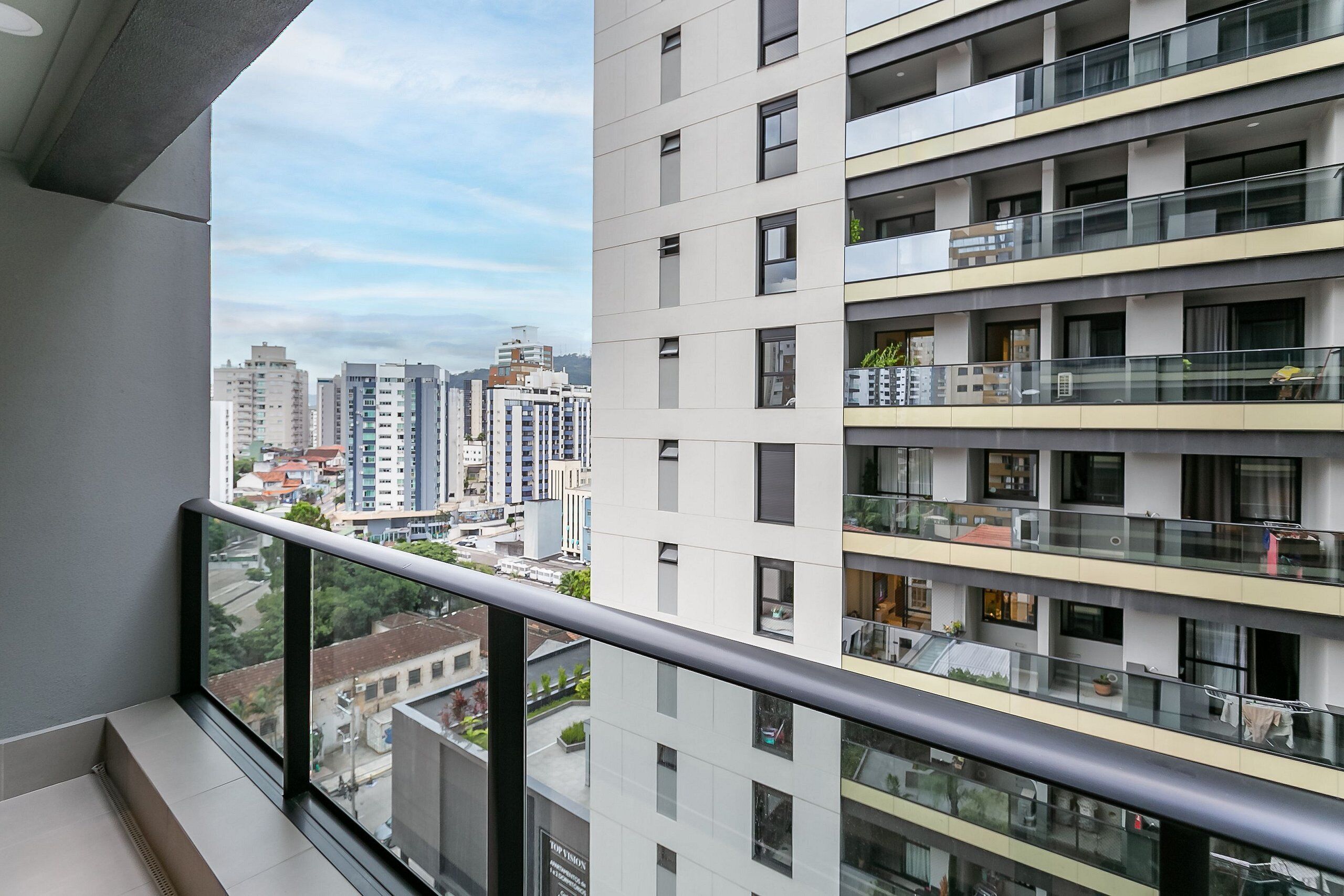 A high-rise apartment building with multiple balconies, large windows, and a cityscape view.