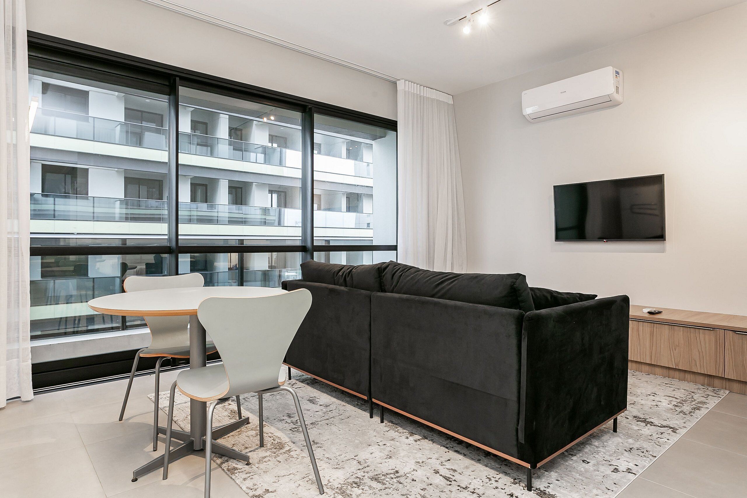 A modern living room with a black sofa, a round table, and two chairs.