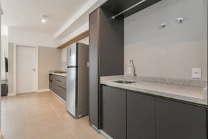 Una cucina moderna con mobili scuri, un piano di lavoro in granito ed elettrodomestici in acciaio inossidabile.
