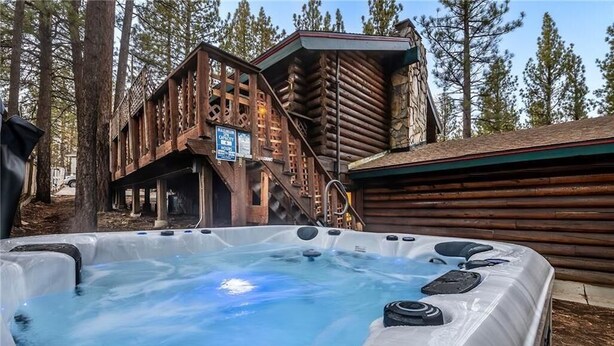 Un bain à remous se trouve devant une cabane en bois, et un escalier mène à une terrasse.